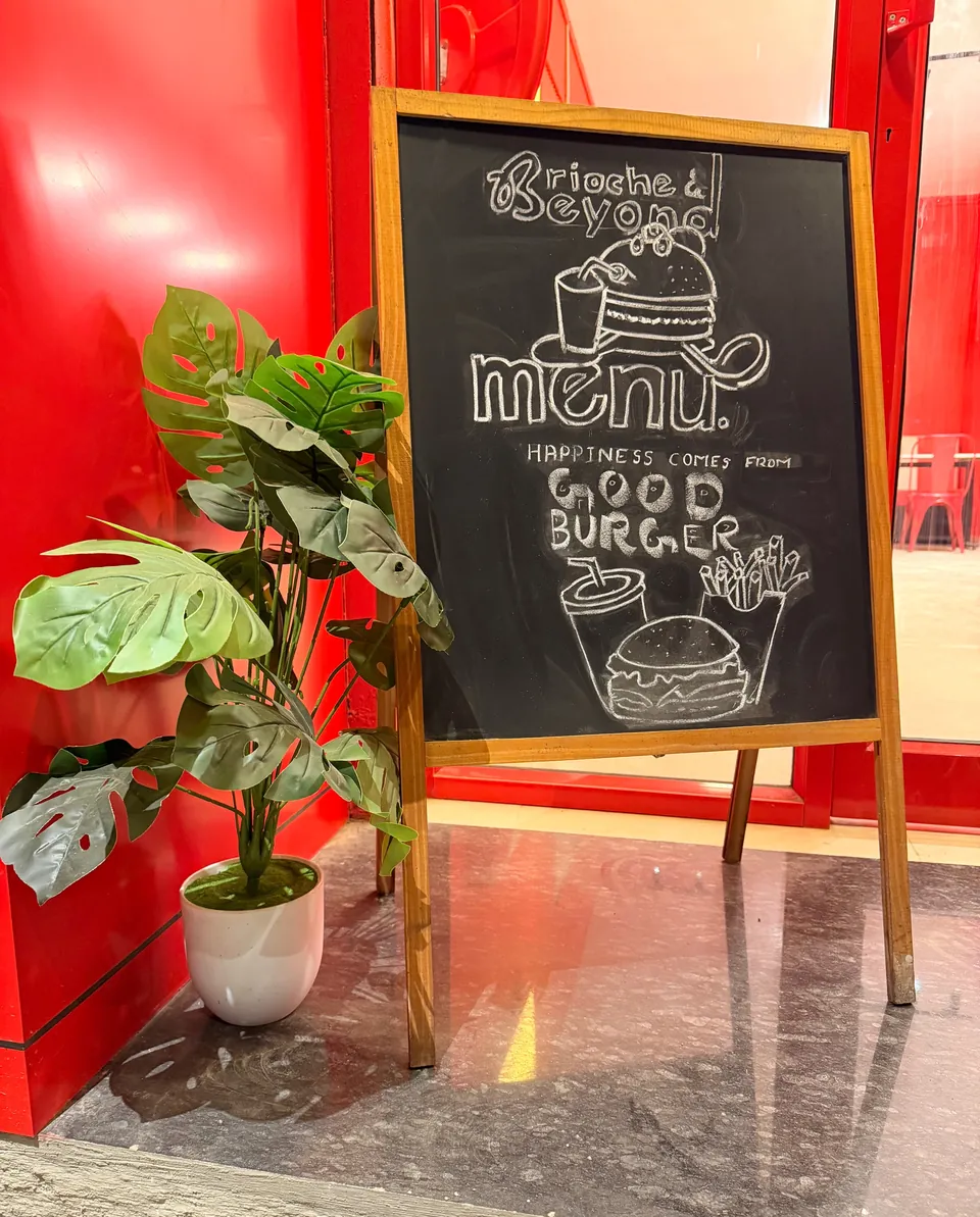 Chalkboard outside Brioche & Beyond that reads happiness comes from good burger