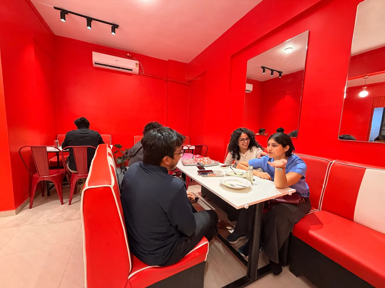 Friends chatting in a red and white booth at Brioche & Beyond