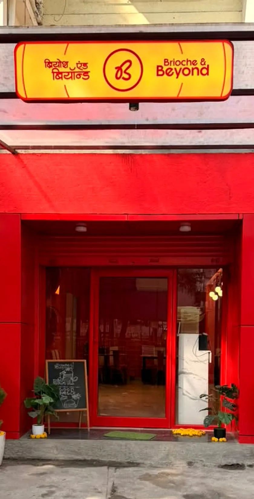 The red Brioche & Beyond storefront with its yellow lightbox sign in Kothrud